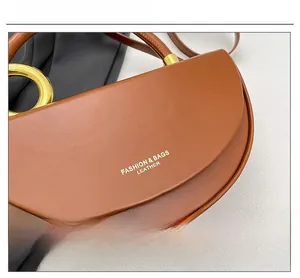 Detail of matte brown saddle bag with gold ring hardware and leather texture