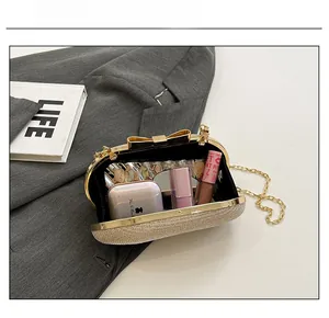 Detail view of gold sequin evening clutch interior capacity with bow clasp and chain strap