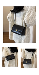 Detailed view of black vintage leather bag with golden rectangular lock and shoulder strap