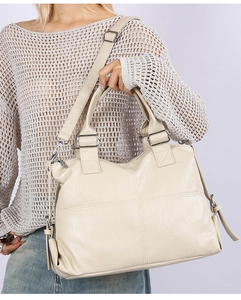 Detail of off-white tote bag showing pebbled leather texture and silver hardware accents