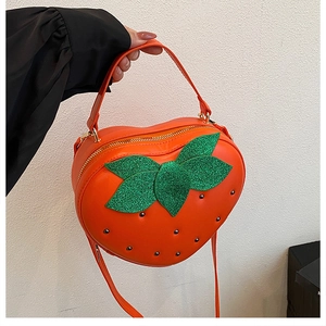 Détail du sac à main en forme de fraise avec feuilles pailletées et clous noirs