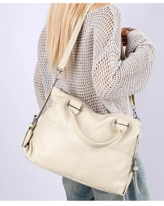 Detail of off-white tote bag showing pebbled leather texture and silver zipper accents