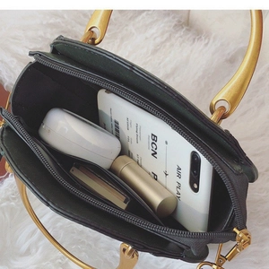 Dark green crossbody bag with gold ring handles and organized interior compartments