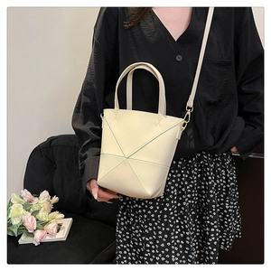 Détail du sac seau crème avec plis géométriques et surpiqûres contrastées