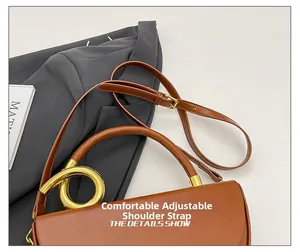 Detail of a brown leather handbag featuring an adjustable shoulder strap and gold hardware