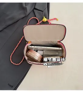 Pink crossbody bag interior showing storage space for phone, lipstick, and gold adjustable ball
