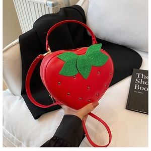 Gros plan du sac fraise rouge en cœur avec feuilles à paillettes et rivets argentés