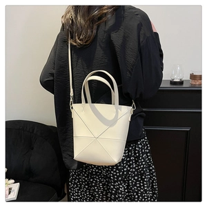 Détail du sac seau blanc cassé avec surpiqûres en croix et finitions métalliques chic