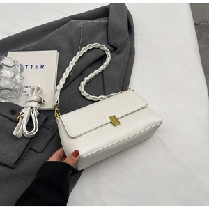 Detail of white faux leather bag featuring a gold buckle and woven textured handle
