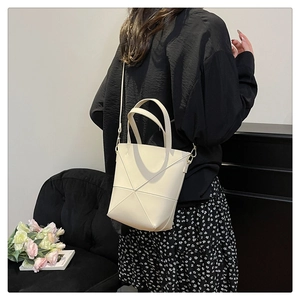 Détail du sac seau crème avec surpiqûres géométriques en X sur cuir mat élégant