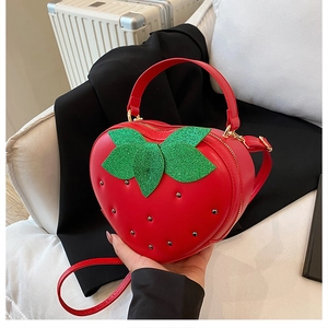 Détail du sac à main rouge en forme de fraise avec feuilles pailletées et clous