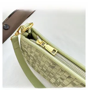 Close-up of smooth gold zipper and woven sage green leather texture on shoulder bag