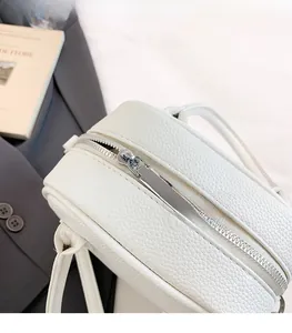 Close-up of silver zipper on white lychee grain leather crossbody bag for women