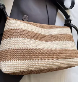 Close-up of woven straw bucket bag featuring beige and brown stripes with leather strap