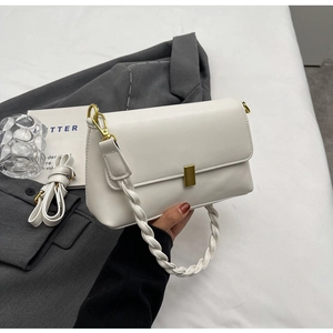Detail of white leather shoulder bag featuring braided handle and gold buckle closure