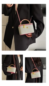 Detail of grey mini crossbody bag with pink trim, gold flower hardware and chain strap