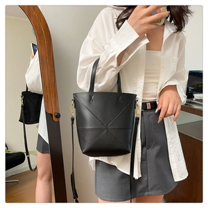Détail du sac seau noir avec texture matelassée en losange et ferrures métalliques dorées