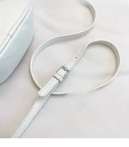 Close-up of adjustable white litchi leather strap with silver metal buckle and stitching