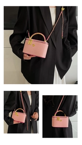 Detail of pink crossbody bag featuring a gold camellia adjustment ball and chain strap