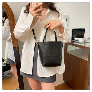 Détail du sac seau noir avec coutures géométriques présenté dans un décor intérieur