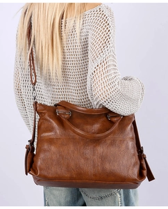 Detail of a brown large capacity shoulder bag with a vintage textured finish on a model