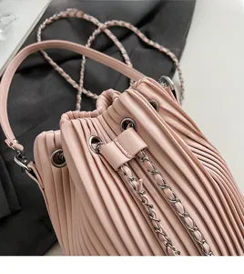 Detail of light pink pleated bucket bag showing leather texture and silver chain strap