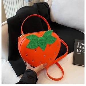Détail du sac fraise avec feuilles vertes scintillantes et rivets métalliques décoratifs
