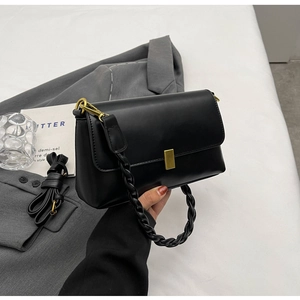 Detail of black leather crossbody bag featuring gold buckle and dual strap options