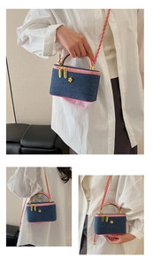 Close-up of blue denim quilted bag with pink trim, gold handle, and metal logo detail