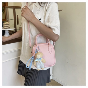 Pink lychee texture crossbody bag with cute brown teddy bear charm in a cafe setting
