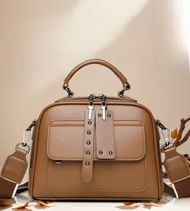 Close-up of retro brown lychee leather handbag with decorative rivet pockets and strap
