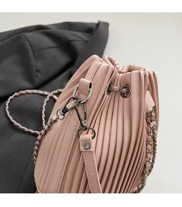 Close-up of pink pleated bucket bag featuring drawstring and silver chain hardware