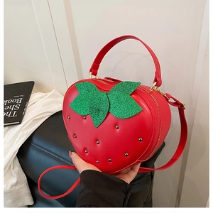Détail du sac bandoulière fraise rouge avec feuilles vertes et finition en similicuir