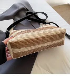 Detailed view of the woven straw bucket bag with striped pattern and slim black strap