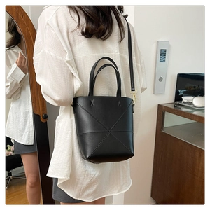 Détail d'un sac seau noir avec coutures géométriques et boucles en métal doré