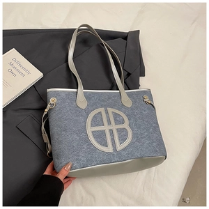 Close-up of gray felt tote bag with round AB logo patch and silver leather strap details
