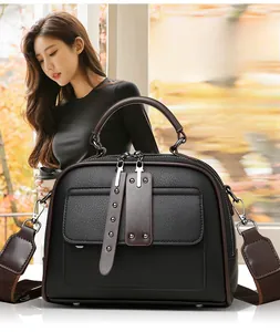 Detailed view of black lychee texture cowhide handbag with brown trim and wide strap