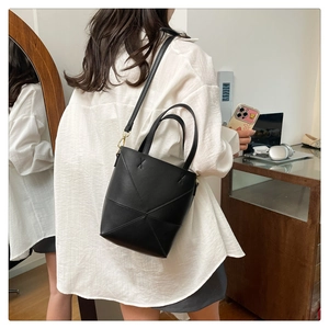 Détail d'un sac seau en cuir noir minimaliste avec coutures géométriques sur un mannequin