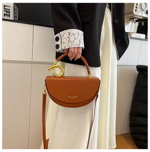 Detail showing brown leather half-moon handbag with unique twisted gold metal handle