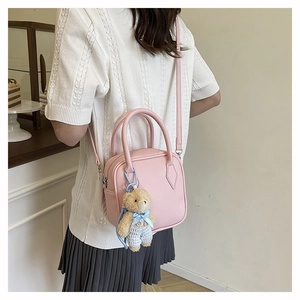 Pink lychee texture square bag with cute bear pendant worn as crossbody by model
