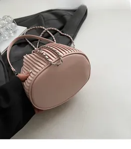 Detail of pink pleated bucket bag showing the texture, flat bottom and metal chain strap