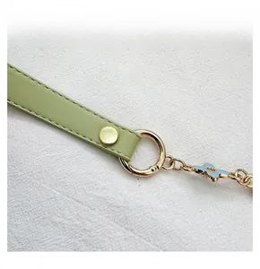 Close-up of green leather strap with gold hardware and blue four-leaf clover pendant