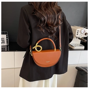 Brown half-moon crossbody bag featuring gold metal knot handle detail and leather strap
