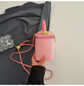 Detail of pink vanity bag with textured fabric, gold chain strap and fruit charm decoration
