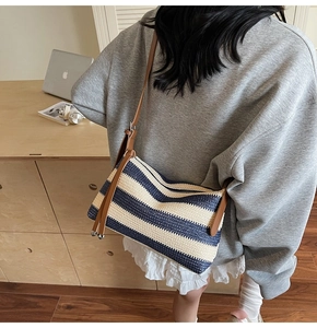 Detail of blue and white striped woven crossbody bag with brown leather strap on model