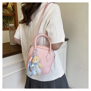 Pink lychee texture crossbody bag featuring a cute teddy bear charm on a white sweater