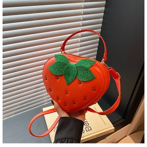 Détail du sac bandoulière créatif en forme de fraise en cuir rouge avec feuille pailletée