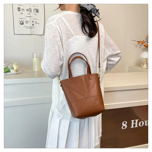 Détail d'un sac seau en cuir marron avec coutures géométriques et garnitures dorées