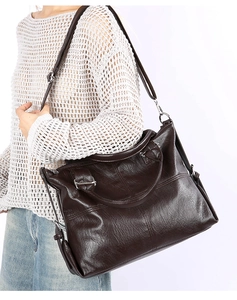 Detail of dark brown lychee texture leather bag with silver metal zipper and shoulder strap