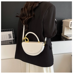 Close-up of a white saddle bag with golden metal ring handle and fashion lettering detail